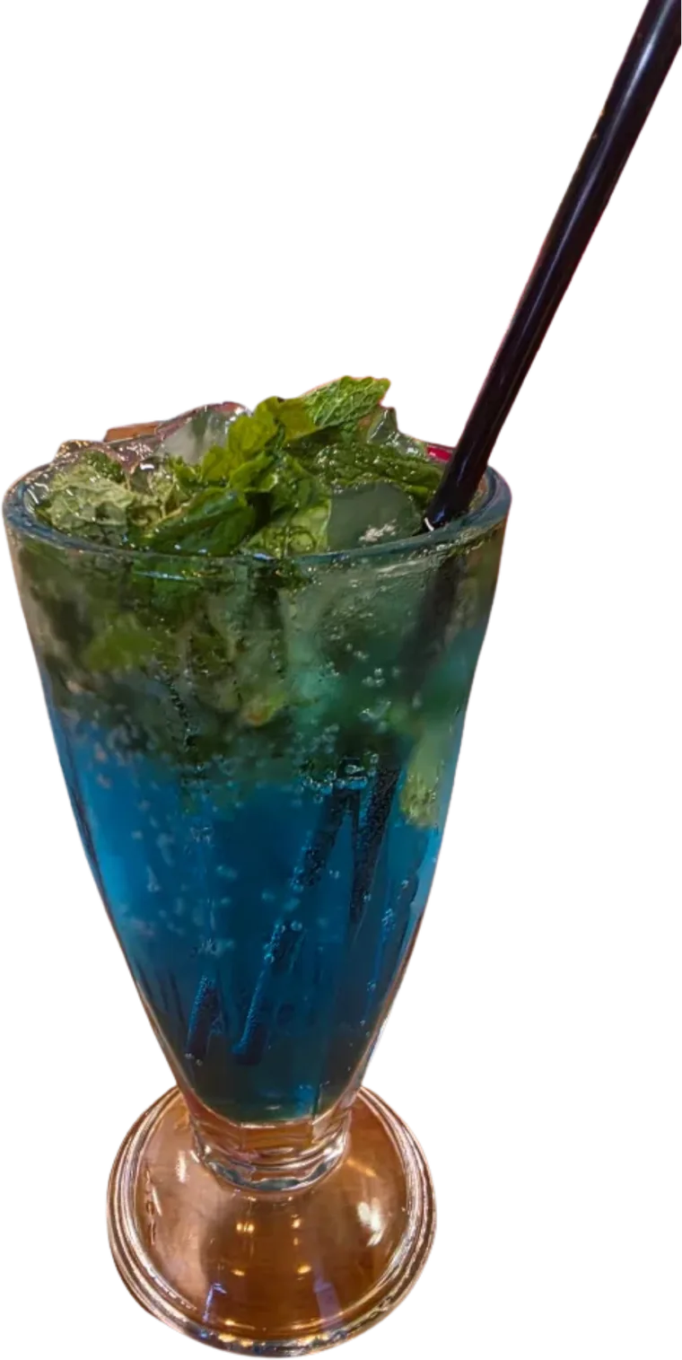 The Blue Lagoon mocktail: blue with crushed ice and fresh mint, a black straw, in a footed glass.