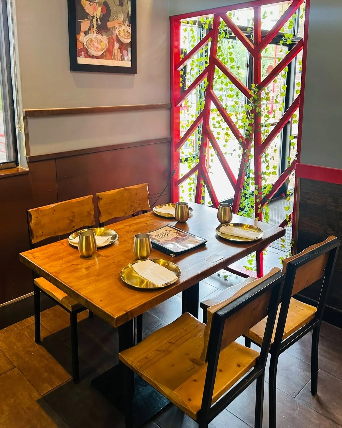 The red chevron screen at Indian Curry with ivy trailing through it and daylight behind, a laid table in front.