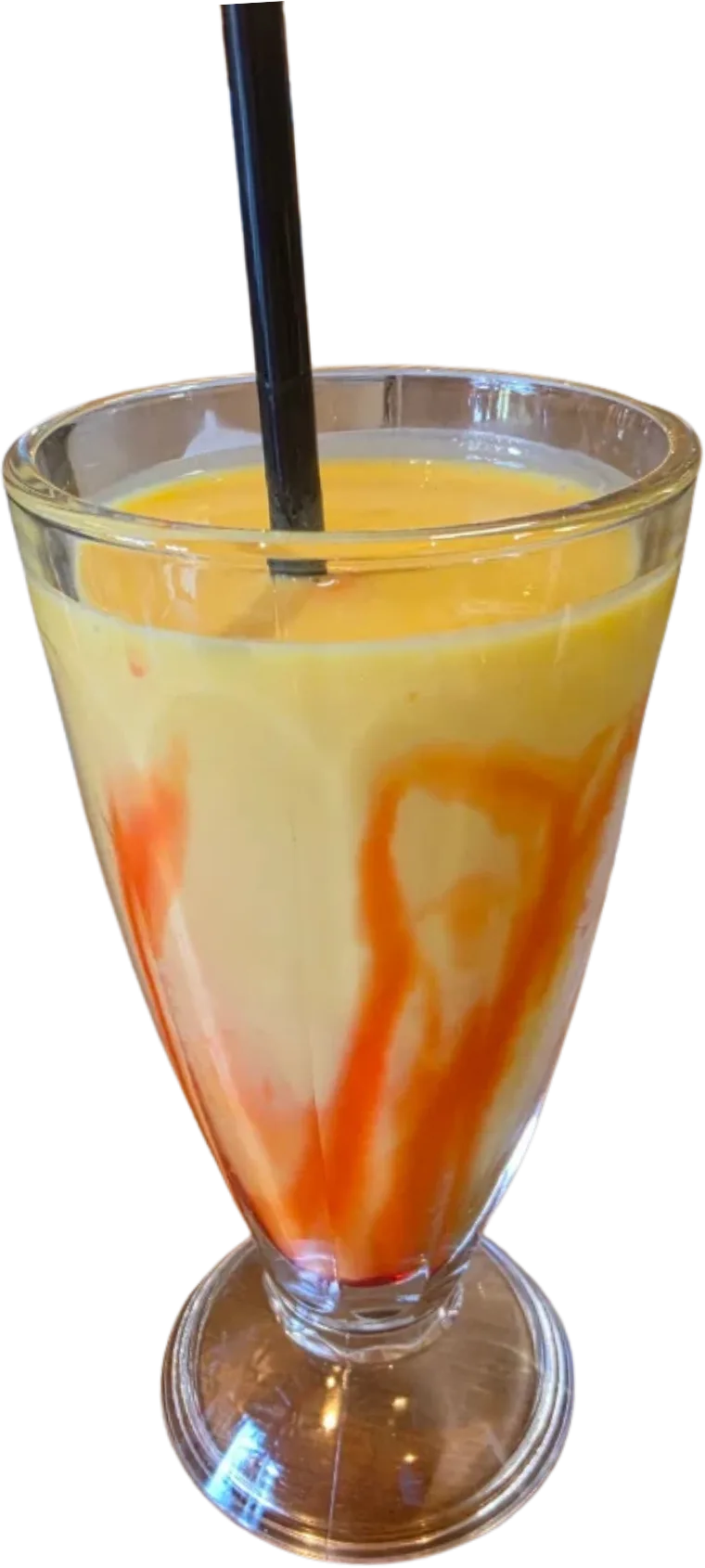 A mango lassi with a red syrup swirl in a footed glass.